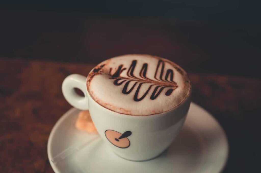 Xícara de café com arte no leite representa a reflexão sobre se cafeína faz bem ou mal para a saúde no consumo diário.
