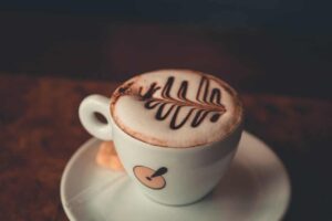 Xícara de café com arte no leite representa a reflexão sobre se cafeína faz bem ou mal para a saúde no consumo diário.