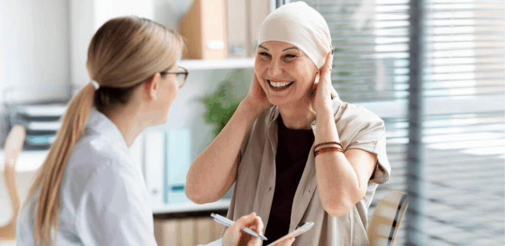 Paciente oncológica sorri durante consulta médica, simbolizando esperança com nova tecnologia de interruptor molecular no tratamento do câncer.