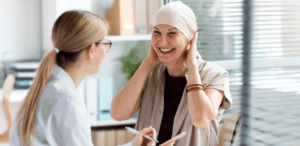 Paciente oncológica sorri durante consulta médica, simbolizando esperança com nova tecnologia de interruptor molecular no tratamento do câncer.
