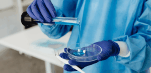 Pesquisador em laboratório manuseando substância em experimento com células-tronco para estudo de regeneração nervosa.