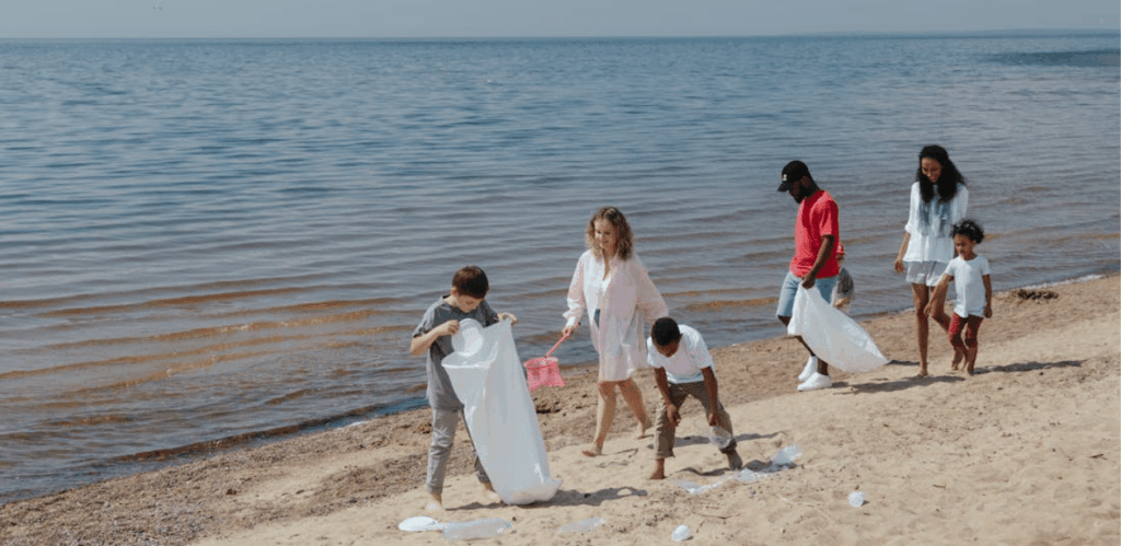 Famílias e crianças participam de mutirão de limpeza em praia, recolhendo lixo e promovendo consciência ambiental no Canal da Barra.
