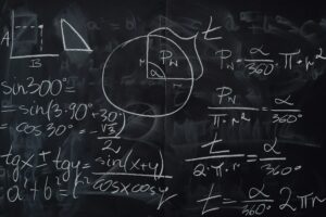 Quadro negro coberto por operações matemáticas escritas com giz branco.