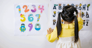 Criança em escola com uma aluna manipulando letras do alfabeto em ambiente educacional