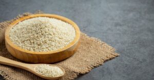 Fibras do psyllium em tigela de madeira com colher sobre tecido rústico